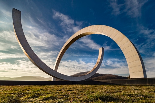 Immagine con nuvole, cielo, archi, prato, monumento, arco, erba, azzurro, colline, scultura, bianco, montagne, terra, curve, arte, due