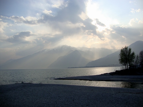 Immagine con nuvole, mare, acqua, montagne, controluce, cielo, alberi, sole, lago, raggi, tramonto, sabbia