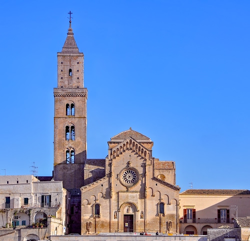 Immagine con rosone, campanile, chiesa, finestre, azzurro, cielo, croce, facciata, bifore, portone, romanico, case, archi