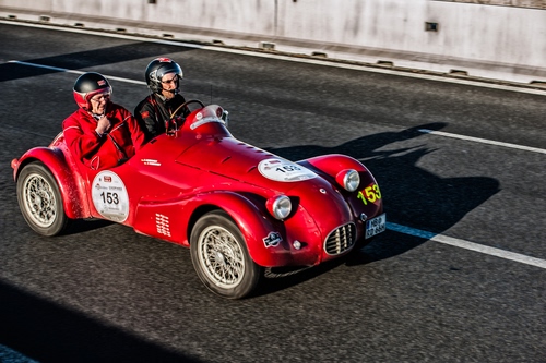 Immagine con strada, ruote, rosso, auto, automobile, due, corsa, persone, caschi, rossa, numeri, epoca, fanali, sportiva, uomini, pilota, gara, raggi, piloti