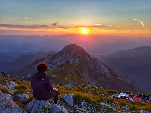 Immagine con sole, tramonto, montagne, erba, panorama, donna, nuvole, verde, rocce, cielo, sensazione, montagna, sassi, vetta, cime, persona, sensazioni, paesaggio, monti