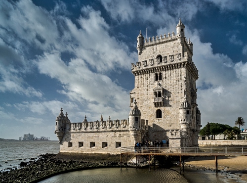 Immagine con torre, nuvole, acqua, mare, cielo, merli, torrette, alberi, lisbona, castello, finestre, ponte, fiume, pontile, portogallo, persone