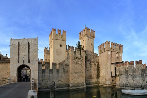 Immagine con castello, torri, merli, acqua, arco, cielo, ponte, fossato, porta, sirmione, azzurro, barca, ingresso, torre, nuvole, mura