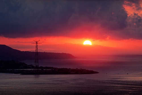 Immagine con mare, tramonto, sole, rosso, controluce, nuvole, acqua, traliccio