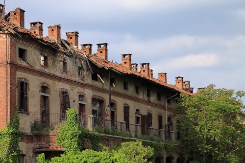 Immagine con alberi, finestre, comignoli, rudere, cielo, tetto, verde, balconi, nuvole, ringhiera, palazzo, casa, camini, abbandono