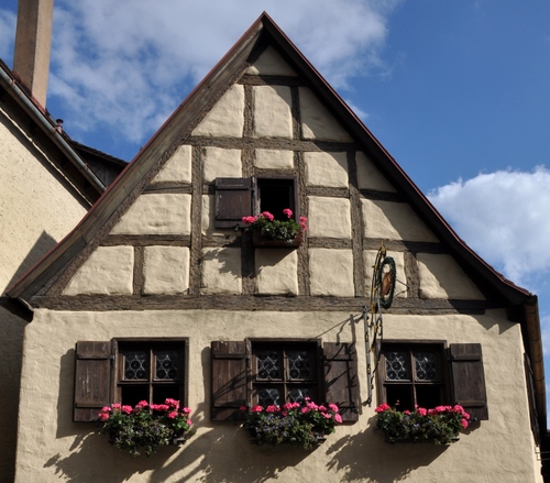 Immagine con finestre, fiori, casa, nuvole, cielo, vasi, tetto, legno, quadrati, insegna, persiane, ante, quattro, azzurro, piante