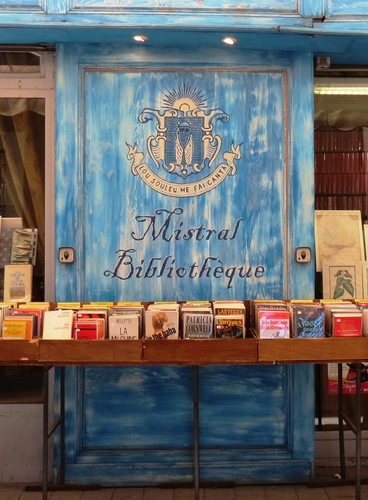 Immagine con libri, stemma, bancarella, azzurro, porta, luci, libreria, biblioteca, leggere, mercatino, vetrina, scritta, scritte, celeste