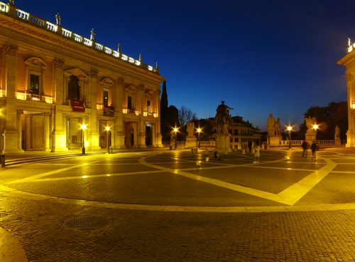 Immagine con piazza, luci, lampioni, monumento, statua, notturno, notte, sera, giallo, roma, palazzo, cielo, passanti