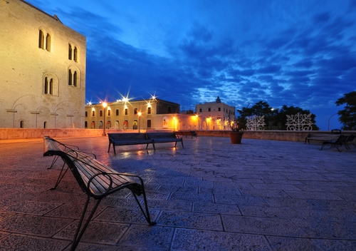 Immagine con piazza, panchina, nuvole, panchine, luci, blu, palazzi, vaso, lampioni, sera, cielo