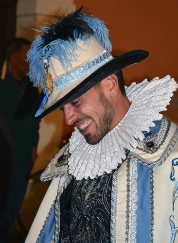 Immagine con cappello, piume, sorriso, costume, uomo, barba, bianco, azzurro, nero, colletto, maschera, gorgiera, mantello, celeste