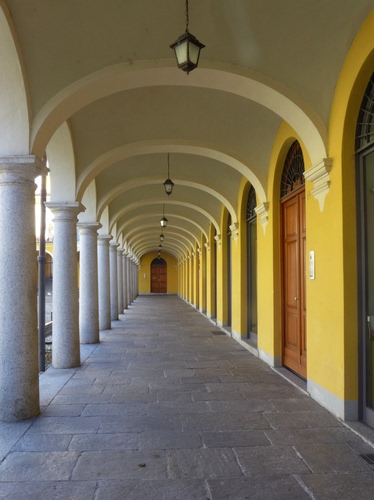 Immagine con colonne, giallo, porte, portico, lampioni, prospettiva, archi, portici, lampade, volte