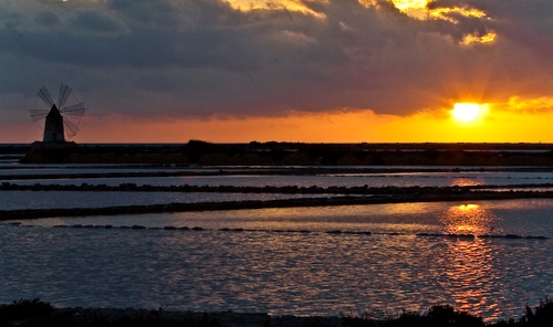 Immagine con mulino, nuvole, tramonto, mare, saline, sole, acqua, pale, giallo, riflesso, cielo, vento, riflessi, arancione, salina