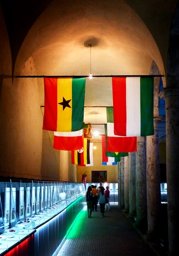 Immagine con bandiere, persone, rosso, verde, bianco, colonne, stella, luci, giallo, colori, museo, vetrine, passanti, bandiera, galleria, mostra, interno, arco, tricolore, esposizione