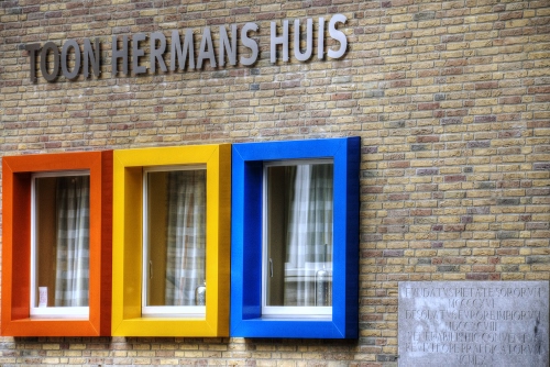 Immagine con giallo, finestre, muro, colori, arancione, mattoni, blu, tende, azzurro, cornici, scritta, targa, tendine, tre, rettangoli, insegna, facciata, vetri