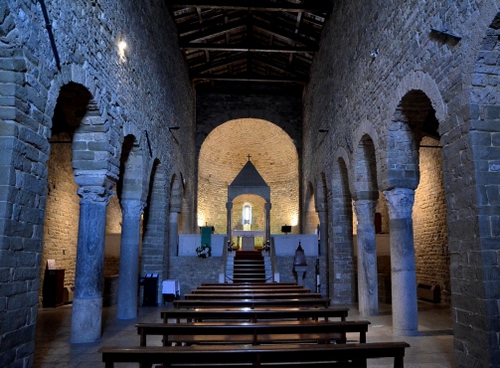 Immagine con colonne, chiesa, altare, archi, interno, banchi, panche, luci, croce, navata, legno, mattoni, pietre