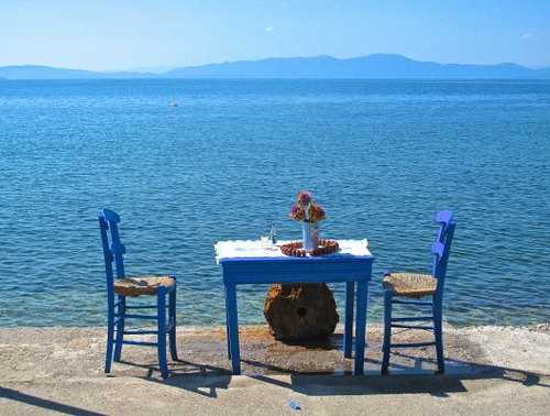 Immagine con sedie, mare, fiori, azzurro, acqua, vaso, tavolino, tavolo, due, montagne, bianco, cielo, ombra, blu