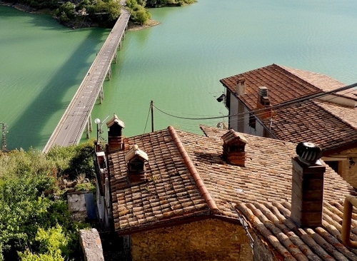 Immagine con ponte, tetti, case, comignoli, verde, acqua, fiume, alberi, tegole, lago, strada, coppi, fili, ombra, rami, cavi
