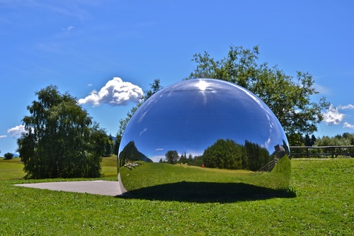 Immagine con alberi, cielo, prato, verde, azzurro, riflesso, nuvole, sfera, erba, riflessi, piante, palla, vetro, specchio, bolla, semisfera