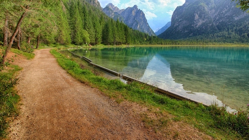 Immagine con lago, alberi, montagne, acqua, strada, verde, riflessi, erba, riflesso, sentiero, nuvole, cielo, bosco, montagna, sterrato, specchio